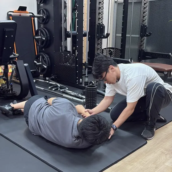 マットにあお向けになったお客様の姿勢を、トレーナーが整える様子